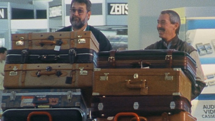 Zwei Männer mit vollbeladenen Gepäckwagen im Flughafen