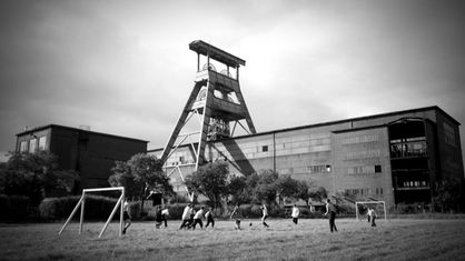 sw-Foto zeigt einen Fußballplatz vor einem Zechengebäude