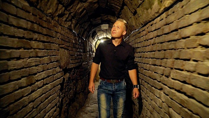 Ein Mann steht in einem gemauerten Abwasserkanal aus der Römerzeit