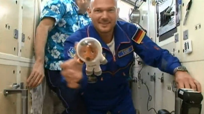 Astronaut Aleander Gerst auf der Raumstation hält die Plüsch-Maus in die Kamera