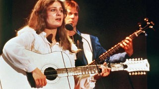 Frau mit Gitarre singend auf der Bühne
