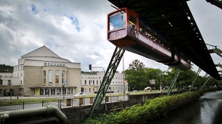 Eine Schwebebahn fährt in Wuppertal am Opernhaus vorbei