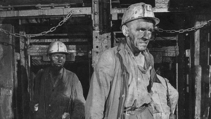 sw-Foto, zwei Bergarbeiter verlassen einen Stollen