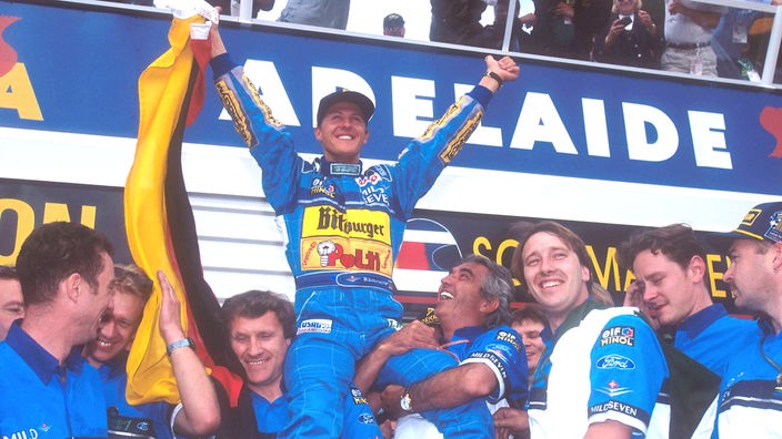 Michael Schumacher jubelnd auf den Schultern seiner Mechaniker