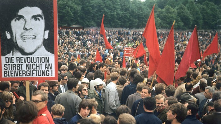 Demonstranten mit roten Transparenten und Rudi-Dutschke-Plakat