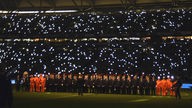 Dunkles Fußballstadion mit Zuschauern und einzelnen Lichtpunkten