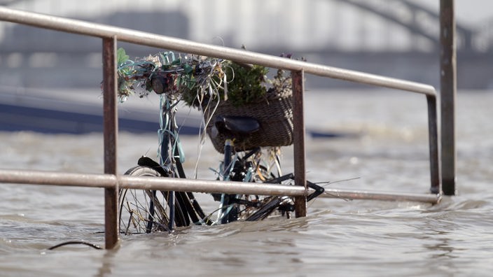 Hochwasser, ein Fahrrad steht im Hochwasser an einem Geländer im Hochwasser