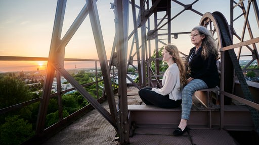 Zwei Frauen sitzen auf einem Dach und blicken über das Ruhrgebiet