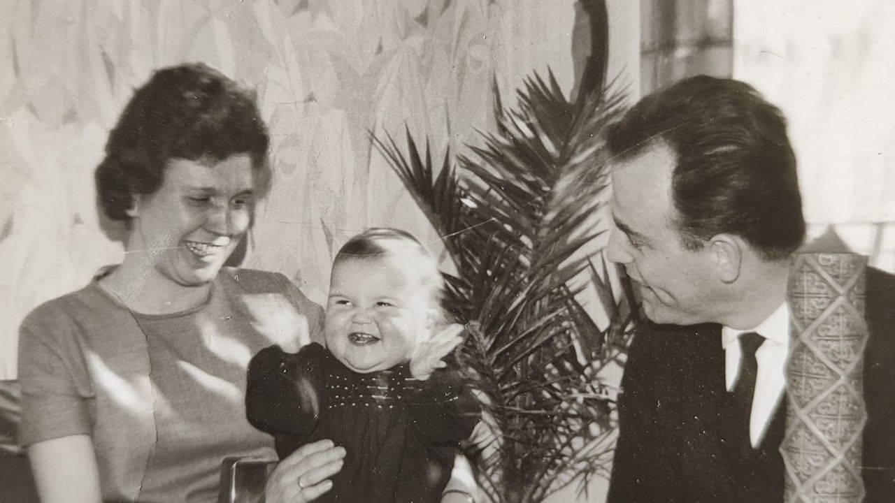 Ein Schwarz-Weiß-Foto von Mutter, Vater und Kind am Tisch.
