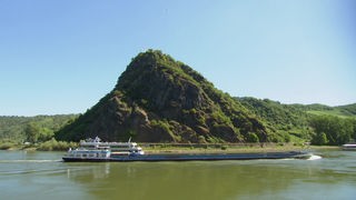Ein Frachtschiff passiert einen Felsen am Rhein.