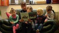 Erzieherin liest drei Kindern aus einem Buch vor