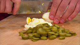Lars Middendorf schneidet Ei und Gurken in den Kartoffelsalat.
