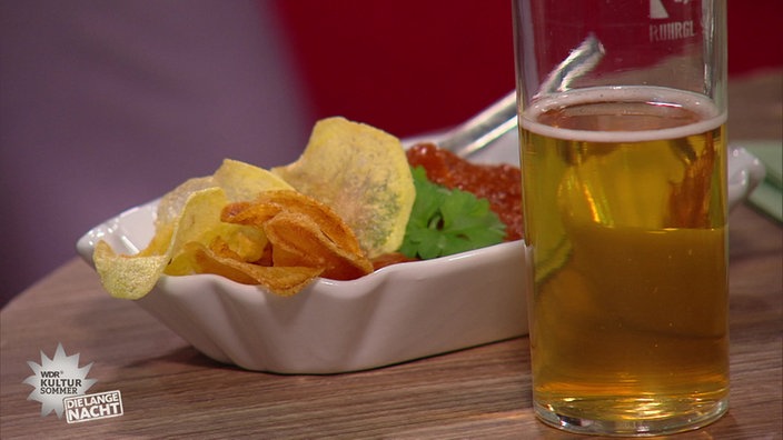 Currywurst in einer Porzellanschale mit Kartoffelchips und ein Glas Bier.