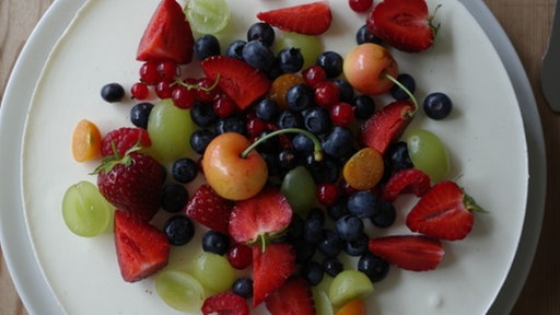 Ein Panna-Cotta-Kuchen auf einer Platte mit verschiedenen Sommerbeeren garniert