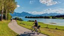 Radfahrerin vor einer Berg-und Seenlandschaft in Bayern.