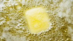 Das Bild zeigt ein Stück Butter, das in einer Pfanne schmilzt.