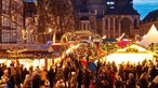 Zu sehen ist der Weihnachtsmarkt vor dem Aachener Dom am Abend.