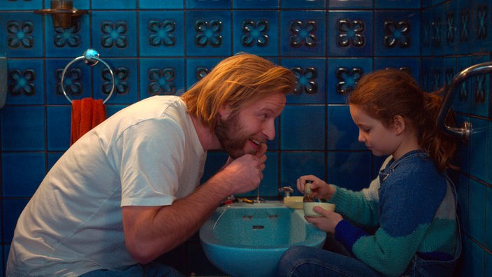 Nelly (Joséphine Sanz) hilft ihrem Vater (l, Stéphane Varupenne) bei der Rasur des Bartes
