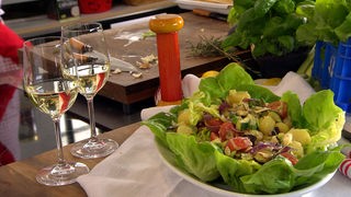 Angerichteter Salat neben zwei Weingläsern