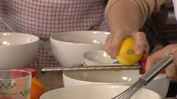 Zitroneschale wird mit einer Reibe bearbeitet