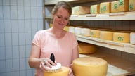 Andrea Strothlüke behandelt einen Käse. 