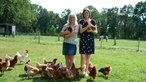 Silvia und Anna mit Huhn auf dem Arm inmitten von Hühnern