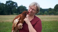 Bärbel Bird mit einem Huhn auf dem Arm. 