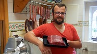 Fabian Goertz mit einem Stück Fleisch in der Hand. 