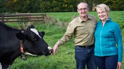 Veronika und Gerhard auf der Weide bei einer Kuh.