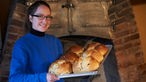 Sabine Klemme vor dem Backofen mit einem Blech voll Brot.