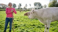 Sarah Konert auf der Weide mit einer Kuh.