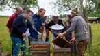 Sebastian Klein mit seinen Gästen bei den Bienenstöcken. 