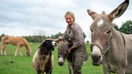 Theesa Cossmann mit Schaf, Esel auf Weide