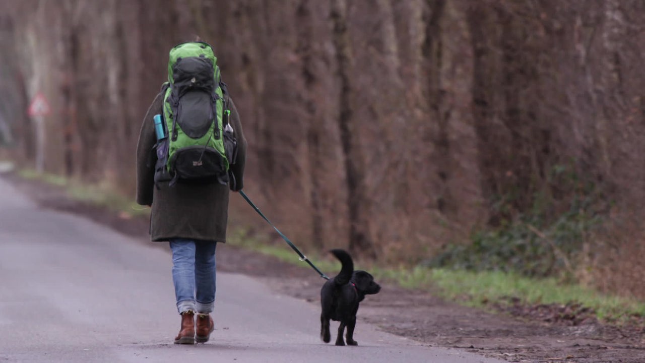 Britta Düsterhus mit Rucksack und Hund auf einer Straße