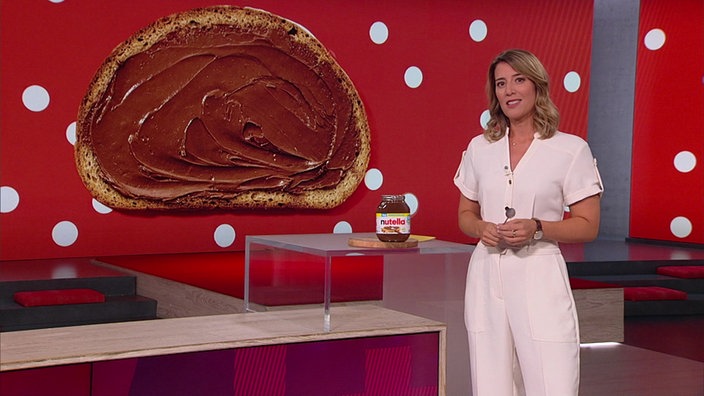 Catherine Vogel steht im Markt-Fernsehstudio. Neben ihr ist ein Glas "Nutella" präsentiert.