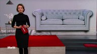 Die Markt Moderatorin im Studio vor einem Bild von einem grauen Sofa