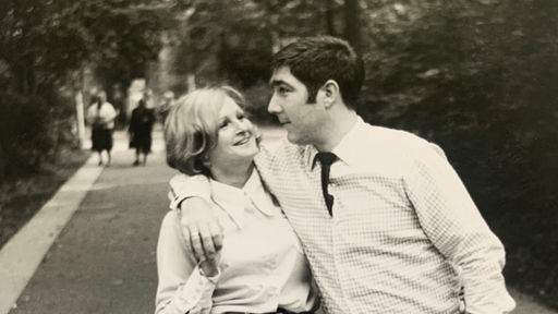 Ein altes Schwarz-Weiß-Foto. Das Paar geht, sich umarmend, durch den Park.