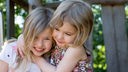 Zwei kleine Mädchen umarmen sich.