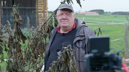 Älterer Mann steht im Garten vor der Kamera