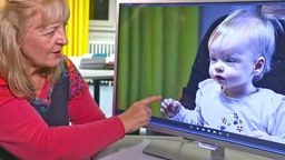 Psychologin zeigt auf einen Monitor mit einem Kindergesicht