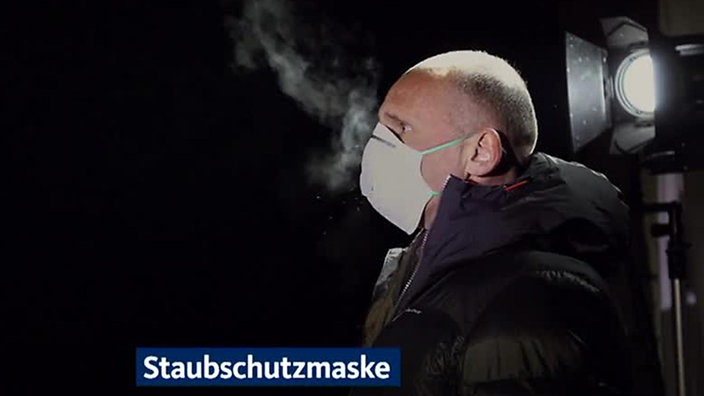 Videostill: Mann hustet durch eine Maske