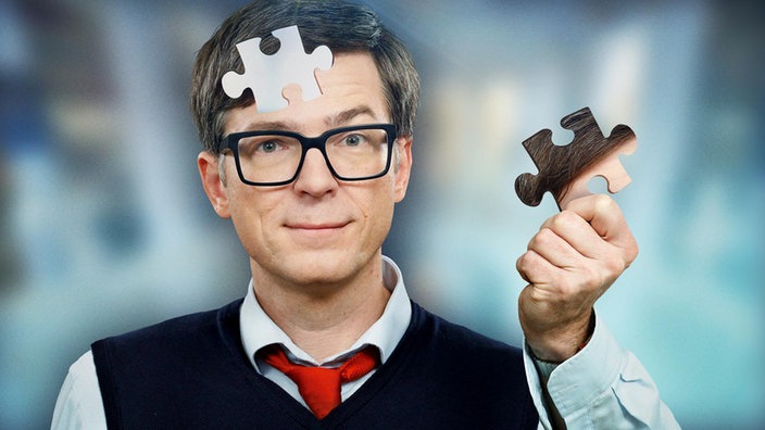 Montage: Ralph Caspers mit einem Puzzle-Stück seines Kopfes in der Hand