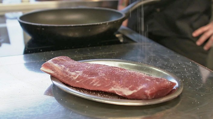 Ein Stück Fleisch wird gesalzen