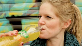 Eine Frau trinkt aus einer Limonadenflasche
