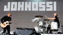 Drummer und Gitarrist von Johnossi spielen nebeneinander auf der Bühne. Im Hintergrund das "Johnossi" - Logo