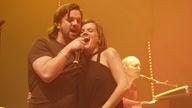 Henning Wehland und die Musikerin Marta Jandova stehen dicht nebeneinander und singen zusammen in das Mikrofon