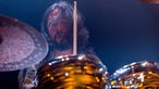 Schlagzeuger der Band Big Sugar lukt hinter seinen Trommeln hervor, das Haar wedelt wild durch die Gegend während er auf seine Trommeln haut