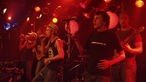 Clueso steht mit seinen Musikern auf der Bühne und setzt zum Finale seines Auftrittes bei Bootleg im August 2006 an