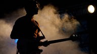 Silouette des Bassisten von Efterklang im Nebel der Bühne