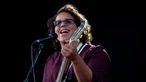 Sängerin der Alabama Shakes mit getönter Brille und Gitarre singt ins Mikrofon und lacht